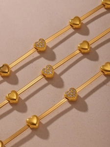 Detail view of 18k gold plated snake chain necklaces with sparkling heart pendants