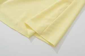 Dettaglio dell'abito in chiffon giallo che mostra cuciture fini e trama del tessuto
