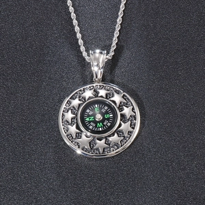 Macro shot of silver stainless steel compass pendant with star relief and twisted chain