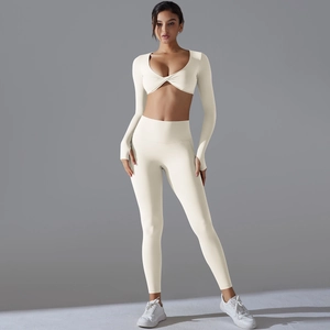 Detail eines cremeweißen Yoga-Sets mit langärmeligem Knotentop und hoher Taillenhose