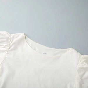 Vue détaillée d'une robe blanche en coton avec manches bouffantes et plis d'épaule