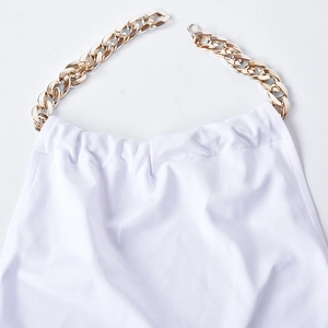 Détail d'une robe blanche à épaules dénudées avec une chaîne en métal doré au décolleté