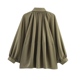 Detail view of the back of an olive green pleated long sleeve jacket with textured fabric