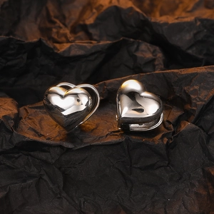 Polished silver heart hoop earrings displayed on premium black textured background