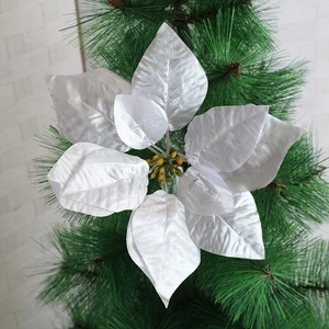 Detail of silver poinsettia flower with textured petals on a green Christmas tree