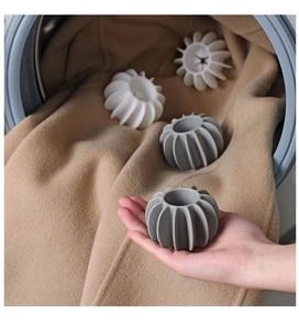 Close-up of a soft grey laundry ball held by hand inside a washing machine for scale
