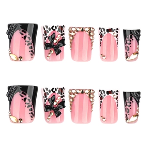 Y2K duckbill flared press-on nails with pink leopard print, black bows, and rhinestones