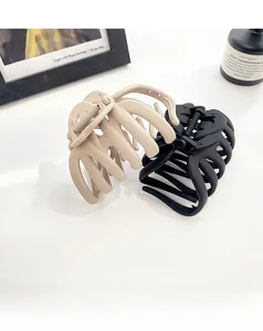 Detail of matte large octopus hair claws in apricot and black on a clean white surface