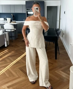Detail of off-shoulder top and high-waist trousers in oat-colored linen fabric