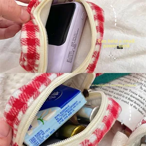 Internal view of cherry-red houndstooth pouch storing a small camera and lipstick