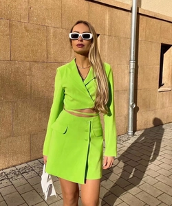 Neon green two-piece suit set featuring a cropped blazer and matching mini skirt outfit
