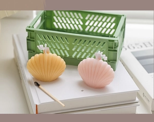 Close-up of shell-shaped candles in yellow and pink on a book for home decoration