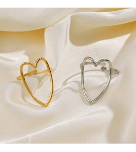 Detailed close-up of gold and silver heart-shaped adjustable rings on white satin
