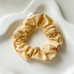 Detailed close-up of a yellow cotton fabric scrunchie on a white artistic display tray