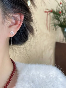 Detailed close-up of long zircon snowflake earrings worn by a model in soft light
