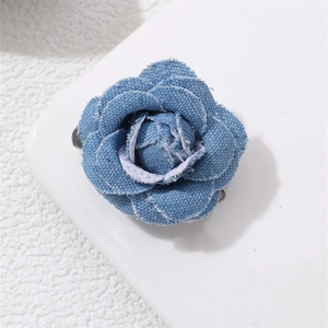 Macro shot of blue denim camellia brooch showing detailed fabric texture and metal clip