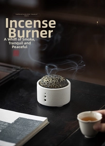 Detailed view of white ceramic incense burner with bronze hollow flower lid on wooden table