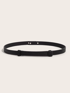 Detail of a thin black leather belt with silver metal buckle and textured finish