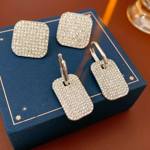 Close-up of sparkling square rhinestone earrings displayed on a luxury dark blue box
