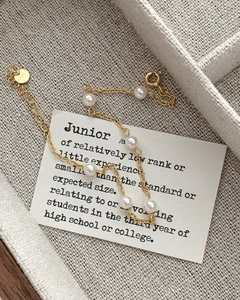 Detail of s925 silver 18K gold-plated beaded bracelet with white round pearls on linen
