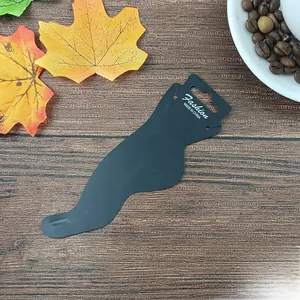 Close-up of black foot-shaped display card for anklets on a dark wooden background