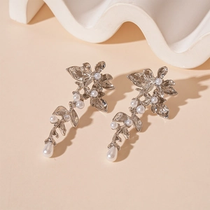 Detail of silver metallic flower earrings with white pearls on a minimalist background