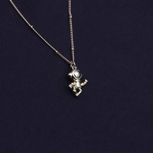 Elegant gold-plated astronaut pendant necklace for women on dark blue textured fabric