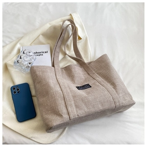 Detailed texture of the large linen tote bag showing the natural fabric weave and fashion label