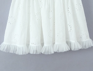 Détail de robe blanche avec broderie florale et ourlet en tulle double transparent