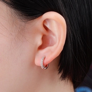 Close-up of pavé-set cubic zirconia hoop earrings with rose gold plating on model's ear