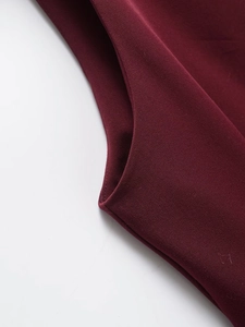 Macro shot of burgundy twill fabric showing fine woven texture and detailed sewing seam