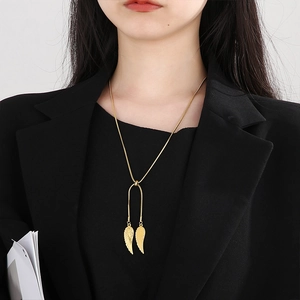 Elegant gold snake chain necklace with angel wing pendant worn by a professional model
