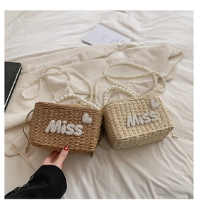 Detail of woven straw bags in brown and beige with pearl miss lettering and heart patterns