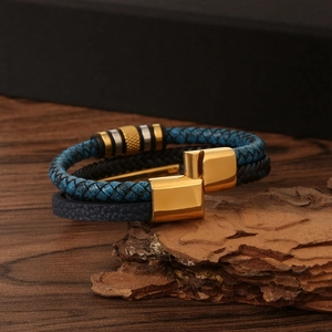 Detail of multi-layer blue and black braided leather bracelet with golden magnetic clasp