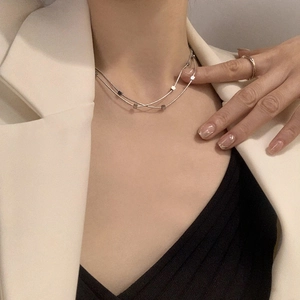 Detail of a layered silver stainless steel necklace with minimalist square pendants