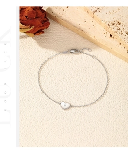 Bracelet cœur en argent avec petite pierre précieuse et fermoir homard sur surface texturée