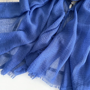 Detailed macro view of royal blue linen scarf fabric with raw edges and crinkled texture