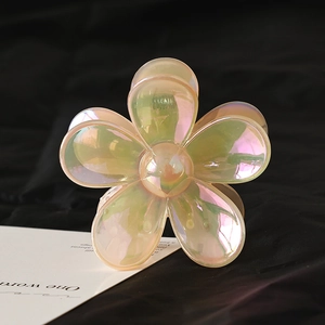 Pearlescent flower hair claw clip with translucent resin petals on dark fabric background