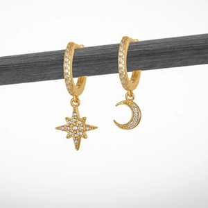 Close-up of asymmetrical gold hoop earrings with sparkling star and moon zircon charms