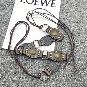 Detail of vintage Y2K belt with brown leather, bronze metal rings and sun flower studs