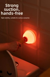 Close-up of a wooden magnetic LED night light with warm red glow on a white tiled wall