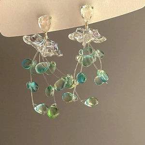 Detail view of long tassel earrings with blue-green gradient drops and floral elements