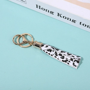 Detail of PU leather tassel keychain with black and white spots and golden metal clasp