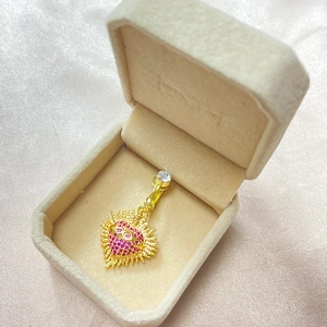 Gros plan d'un clip de nombril cœur doré avec strass roses dans un coffret cadeau