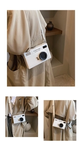White vintage camera box bag with detailed lens design shown on model in neutral outfit