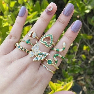 Close-up of gold butterfly and snake rings with green zircon stones on hand
