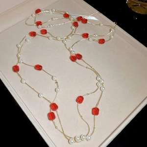 Close-up of elegant gold chain with red faceted beads and white pearls in S-shape