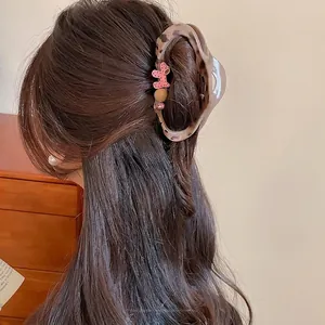 Brown tortoiseshell claw clip with cute puppy design shown on a woman from a 45-degree angle