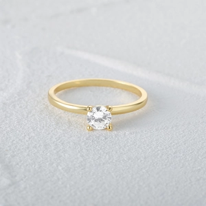 Detailed macro view of gold-tone solitaire ring with four-prong set round cubic zirconia