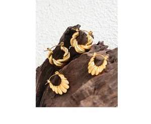Close-up of gold titanium steel hoop earrings with twist and scalloped textures